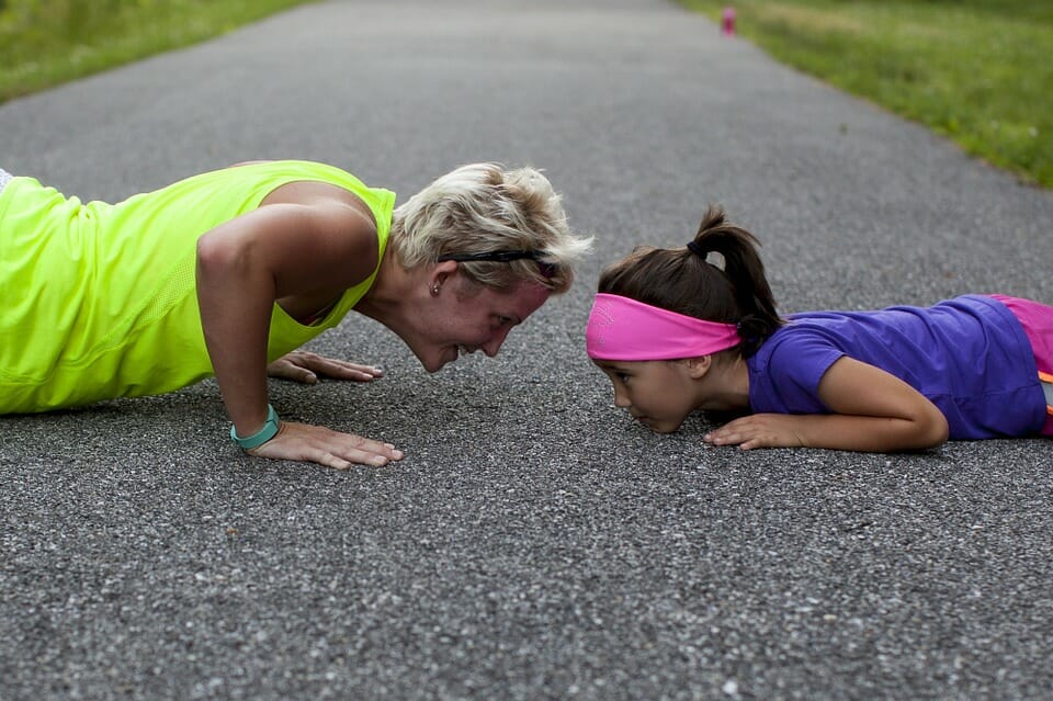 Woman and girl doing push ups on the road