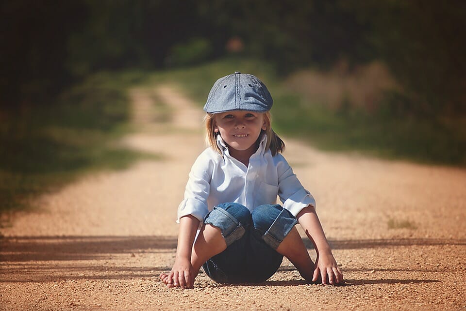 Boy sitting on a dirt road