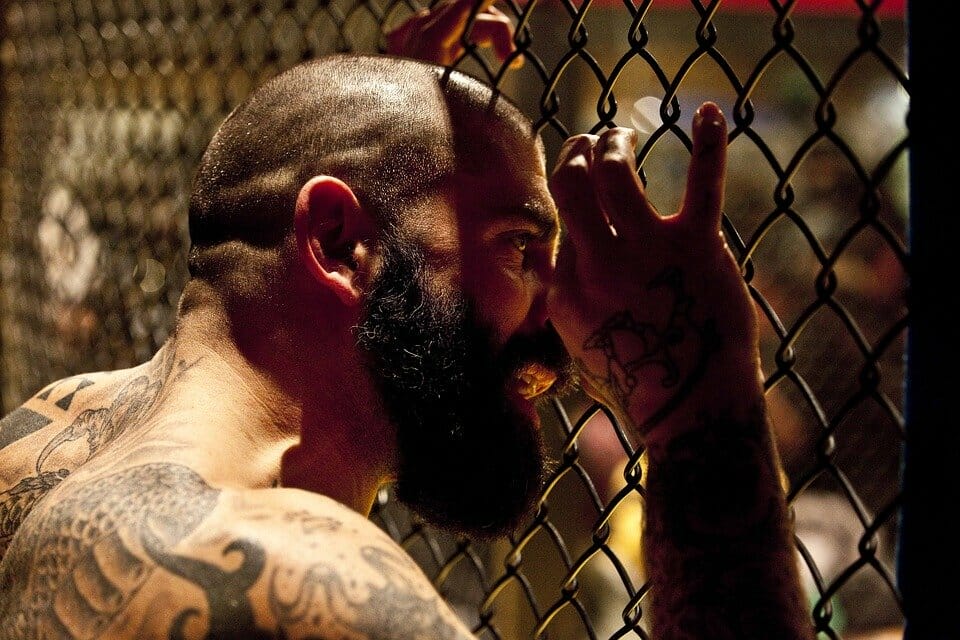 Tattooed strong man behind a fence