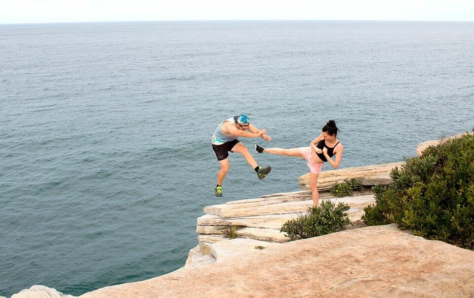 Woman kicking man off a cliff