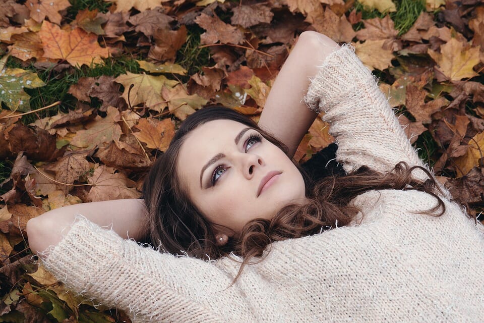 Young woman lying peacefully on a bed of leaves