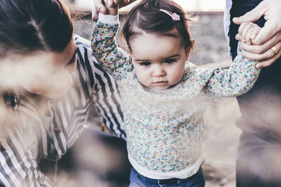 Baby walking holding parents' hands