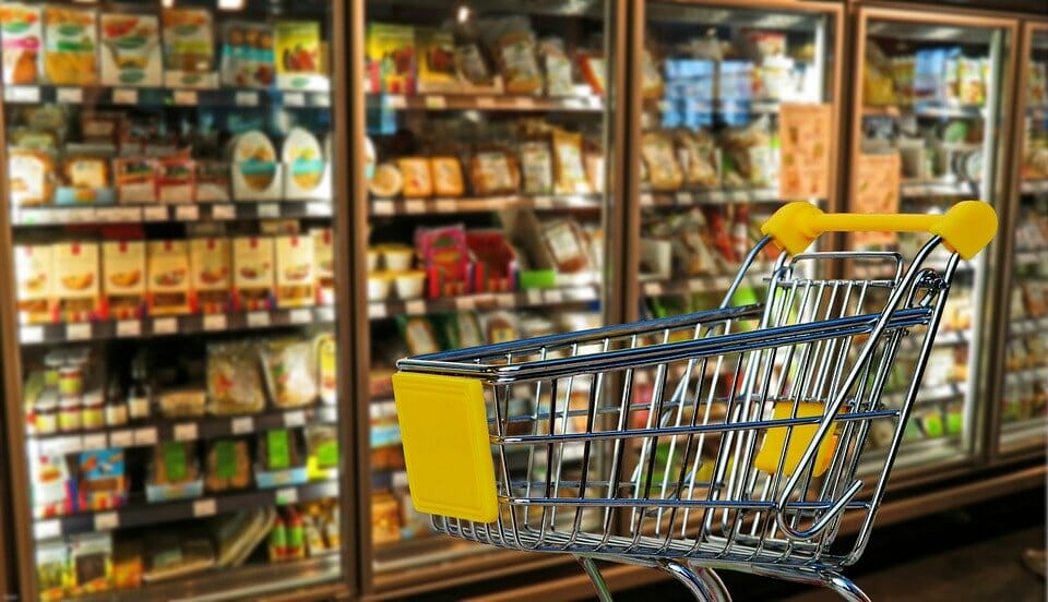 Shopping cart in front of supermarket shelves