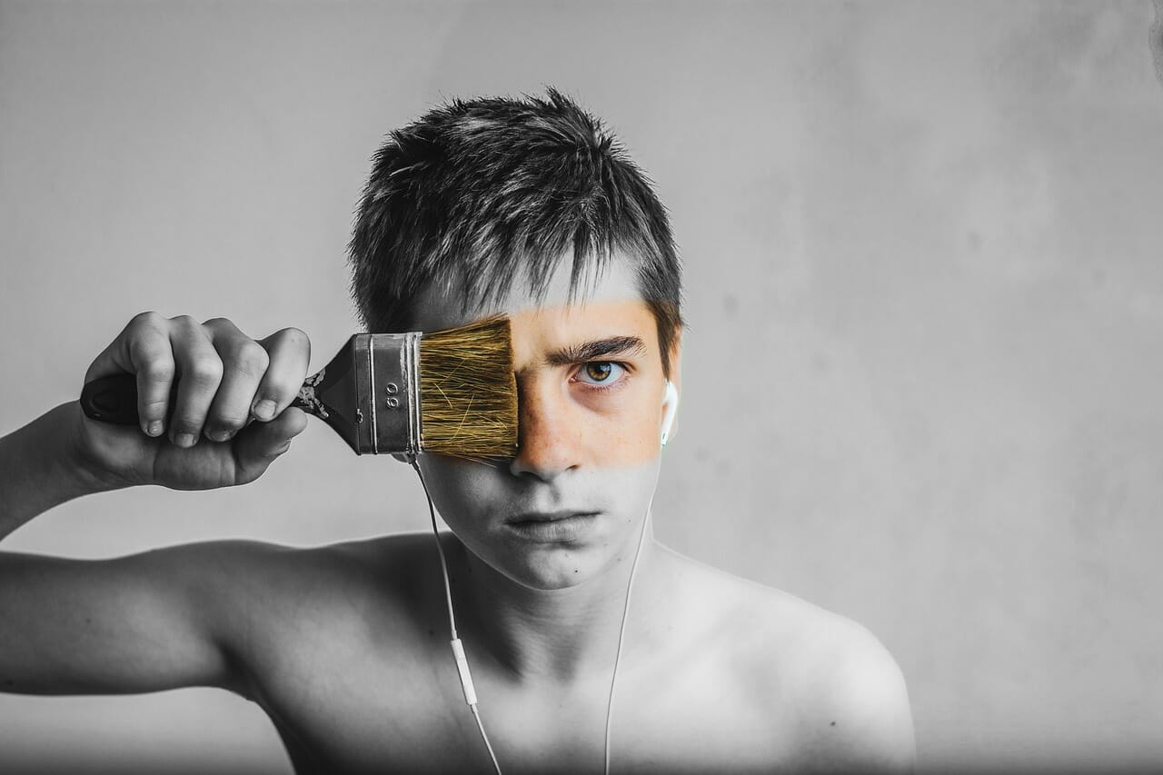 Young man painting face with brush