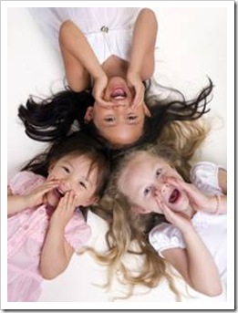3 girls laughing on a bed during a sleepover