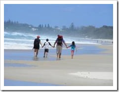 Family walking on a beach holding hands