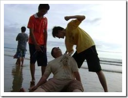 Group of boys hitting fat boy on beach