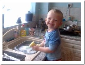 Little boy washing dishes