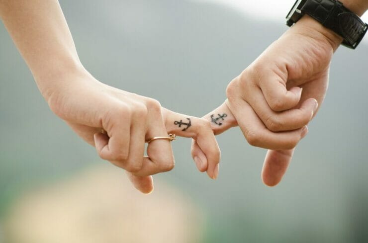 Couple connecting fingers with matching anchor tattoos