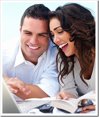 Man and women reading a book and looking at a computer screen together