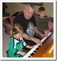 Grandfather playing piano with two grandchildren