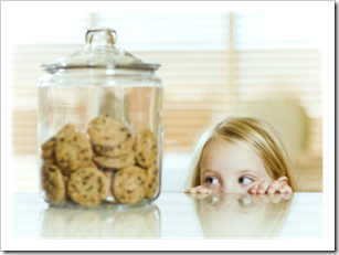 Little girl staring at a jar of cookies