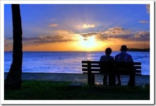 Old couple sitting on a bench a sunset