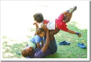 Man playing with two children in the grass