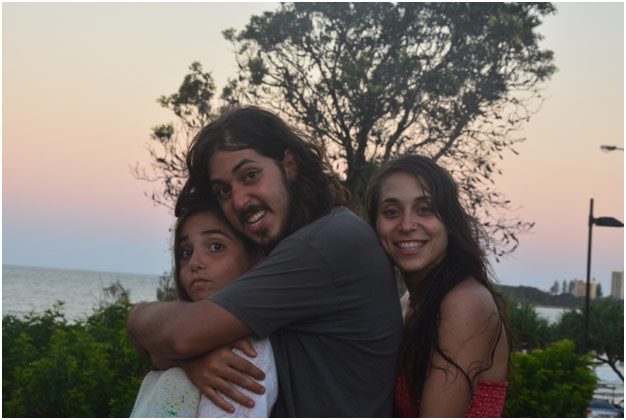 Brother and two sisters hugging in the sunset