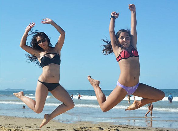 Two sisters jumping on the beach