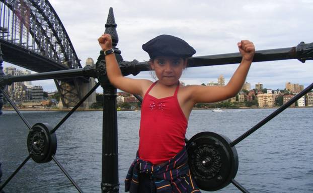 Girl showing her muscles in front of the Sydney Harbour Bridge