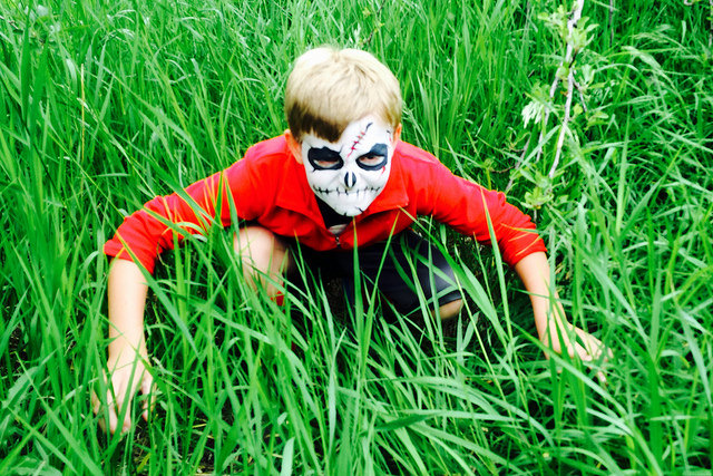 Boy in grass with zombie mask