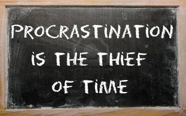 Procrastination is the thief of time written on a blackboard