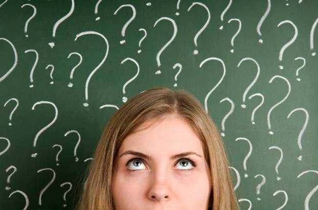 Woman looking up in front of a blackboard full of question marks