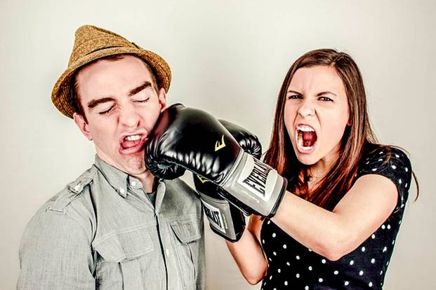 Woman punching man in anger with boxing glove