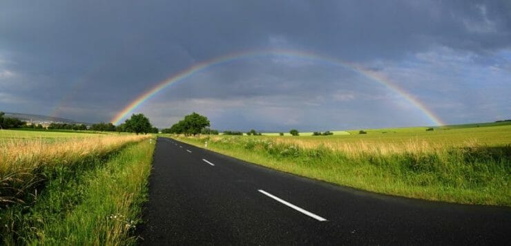 Country road going toward a rainbow