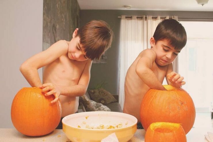 Kinesthetic kids love mess. Two boys cutting out Halloween pumpkins