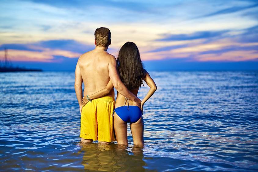 Loving couple in the ocean at sunset