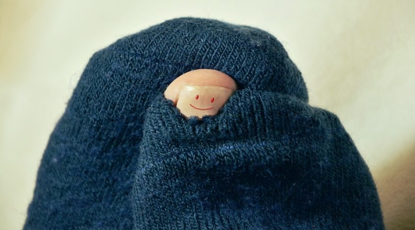 Toe poking through hole in socks with a smile on it