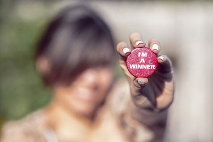 Woman holding up a button that says I'm a winner