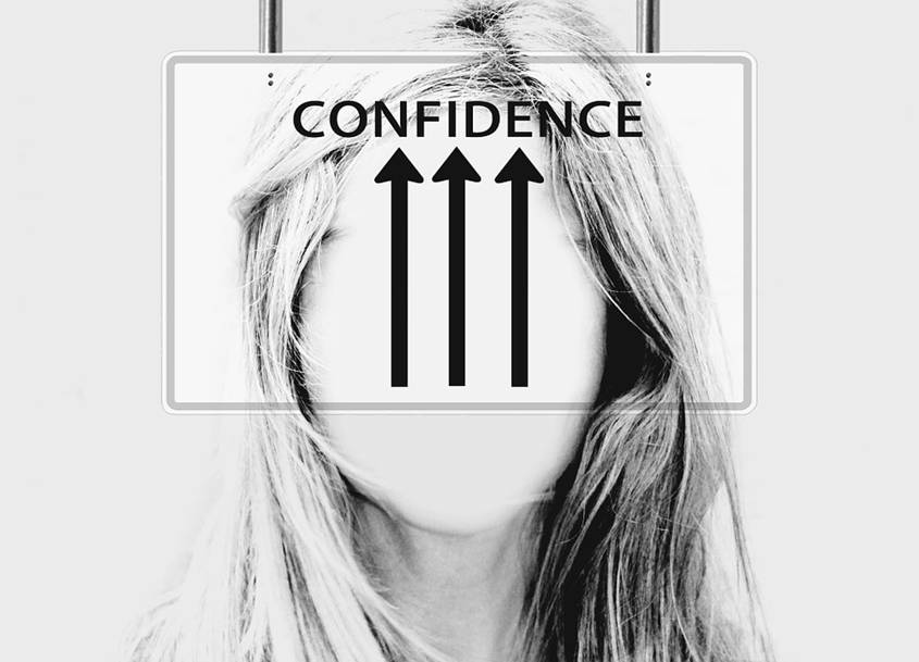 Faceless woman with a sign showing arrows pointing at the word CONFIDENCE