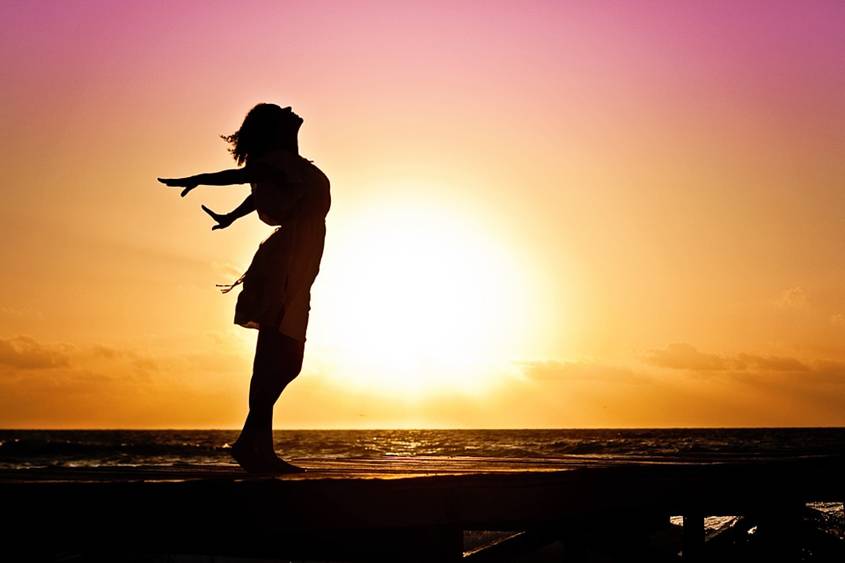 Woman stretching widely on a beach at sunset