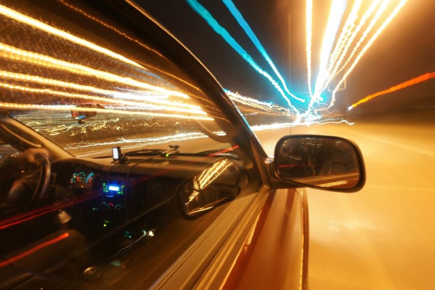 The side of a car on the road at night