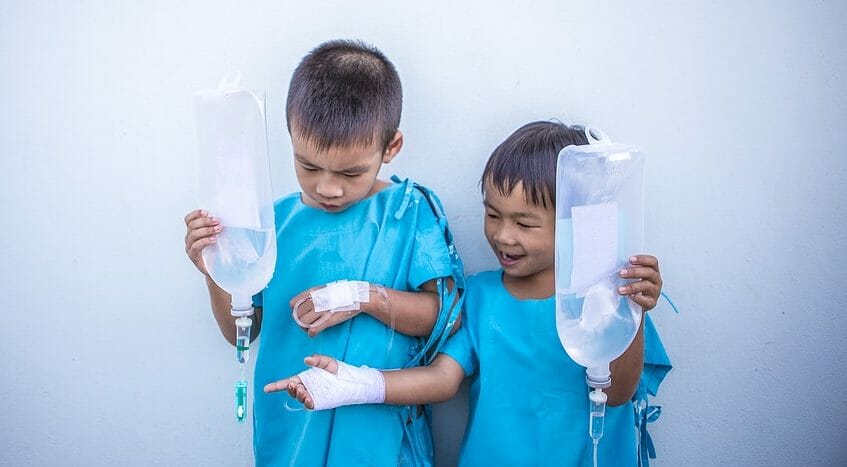 2 boys in hospital gowns with IV drips