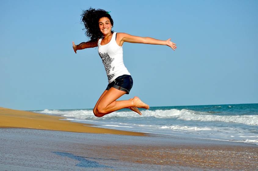 Young woman jumping for joy on a beach