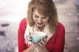 Happy woman holding a cup in the snow