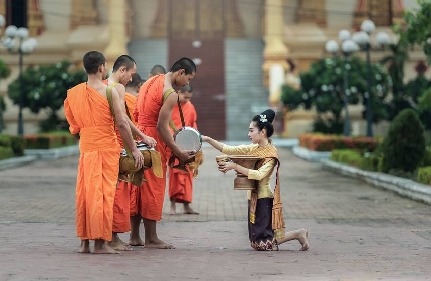 Woman giving offering to Buddhist monks