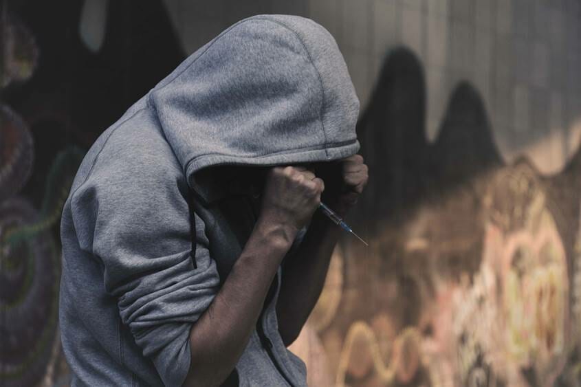 Man in a hoodie holding a syringe