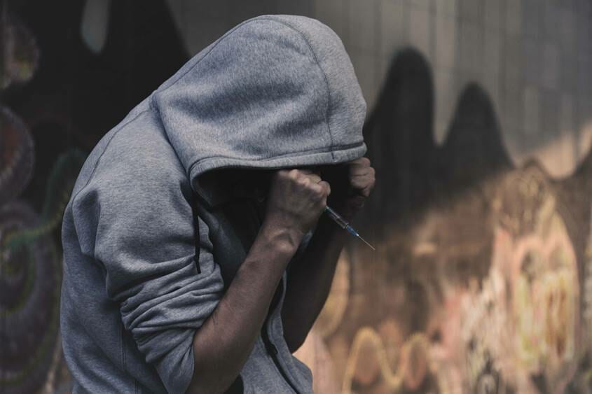 Man in hoodie holding a syringe