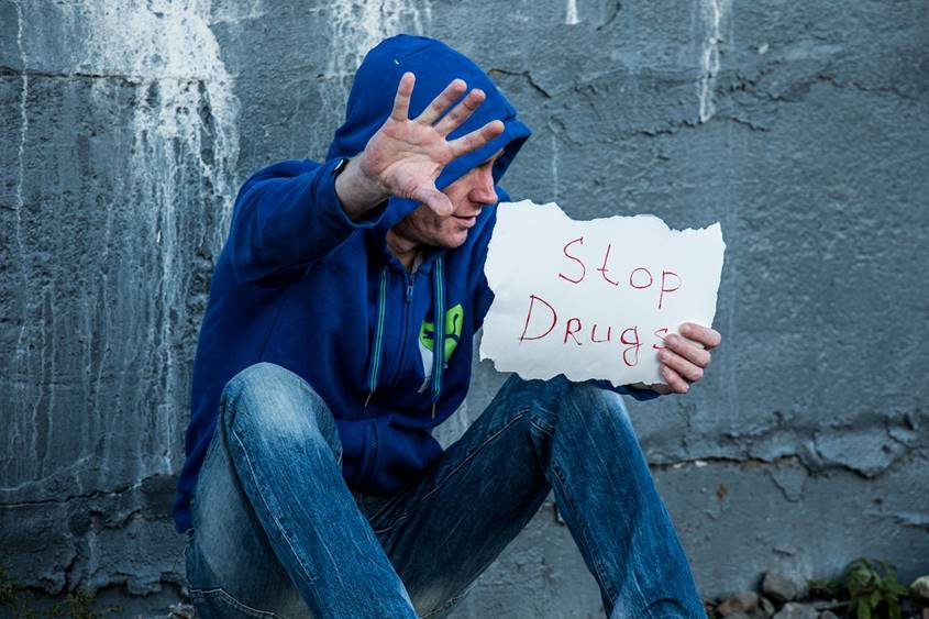 Man in hoodie holding a Stop Drugs sign