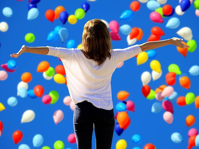 Balloons raining on a happy woman winner