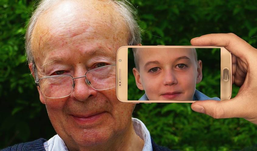 Mobile phone pointed at old man showing a boy