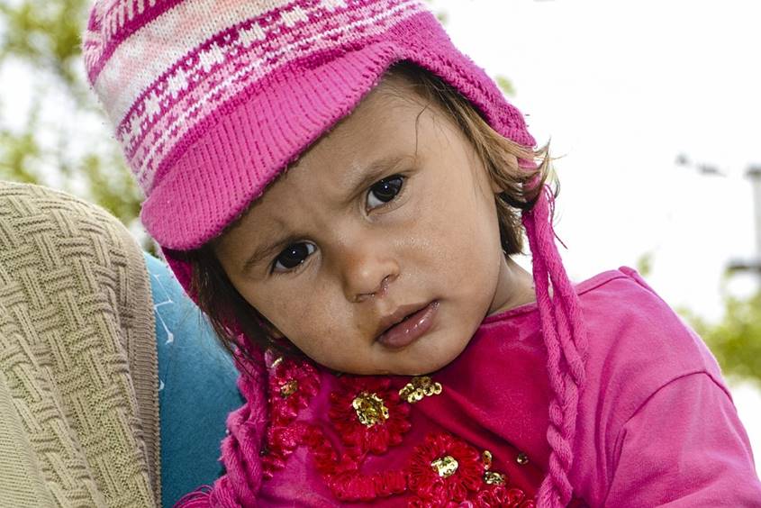 Little girl dressed in pink with a pink knitted hat and a runny nose