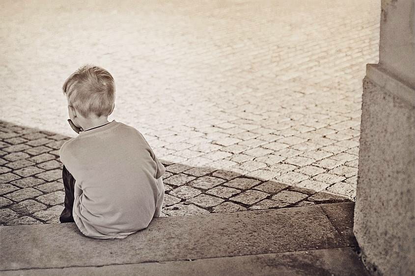 Boy sitting sadly on a stone step after someone said to him "I'm disappointed in you"
