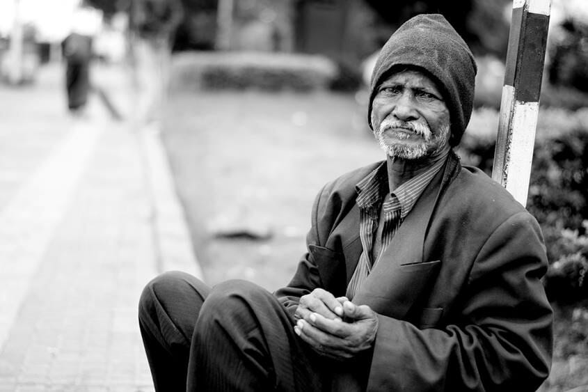 Man sitting on the street in an over-sized suit and beanie