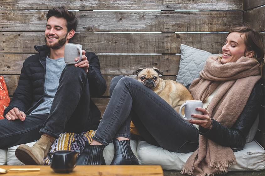 Couple laughing with hot drinks and dog