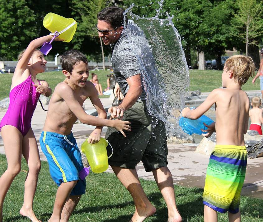 Father playing water games with 3 kids