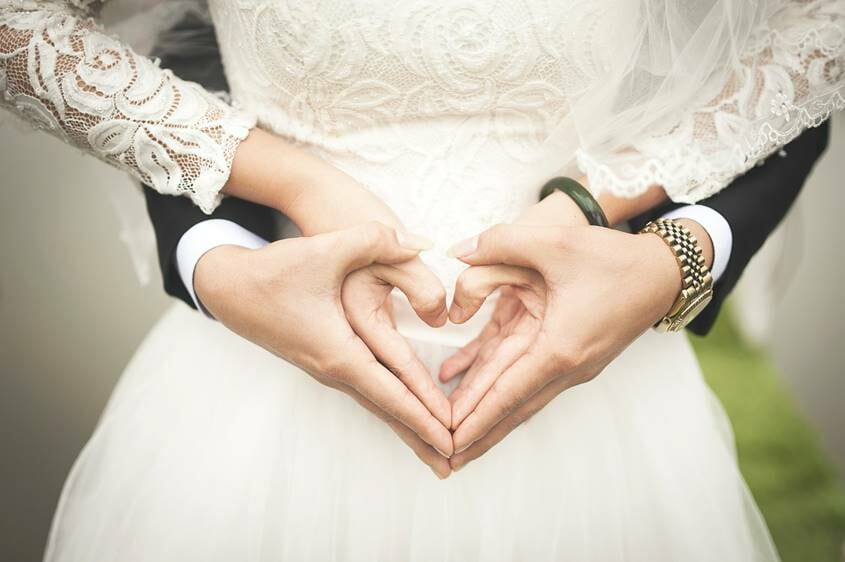 Bride and groom holding their hands in heart shape