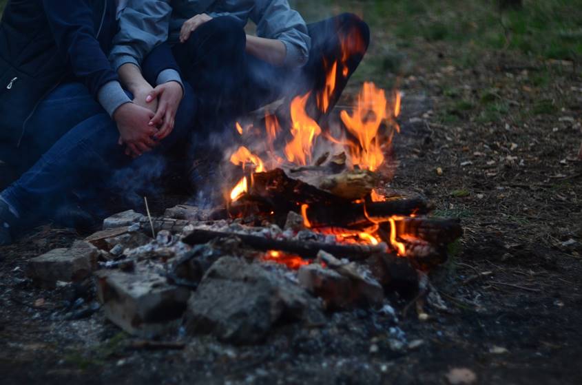 Couple warming up near a campfire