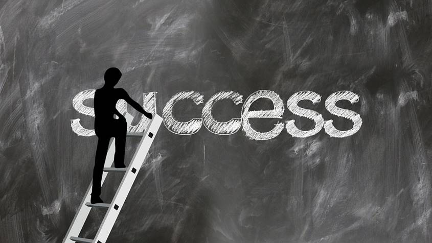 Figure climbing ladder up to the word Success